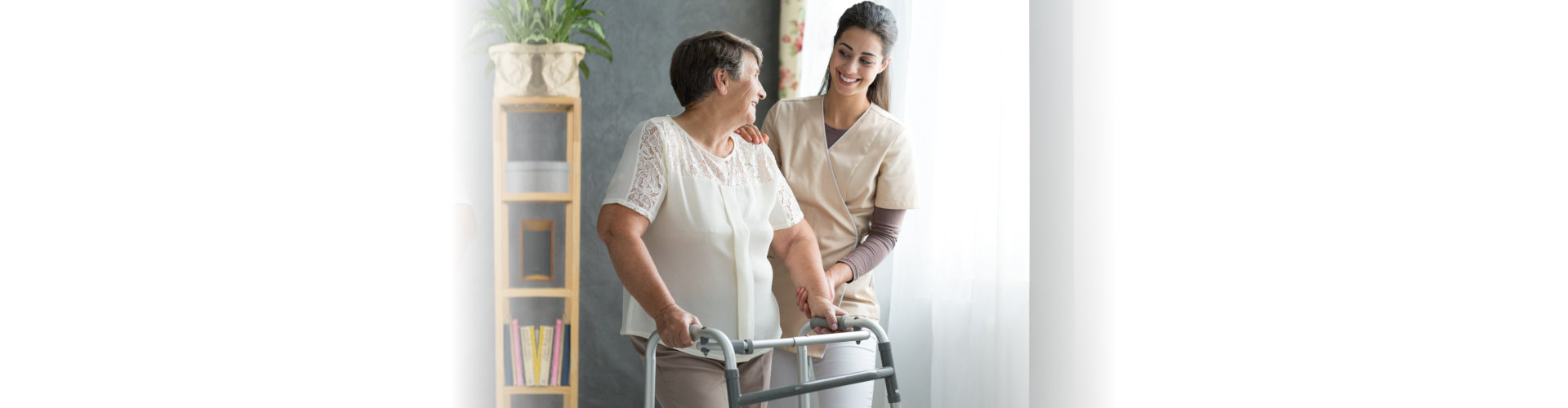Elderly woman using a walker smiling with younger woman